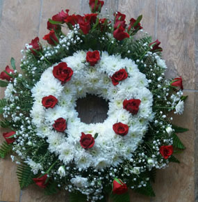 ROUND FUNERAL WREATH WITH RED ROSES AND GERBERAS AND WHITE GYPSOPHILA AND CRYSENTHEM